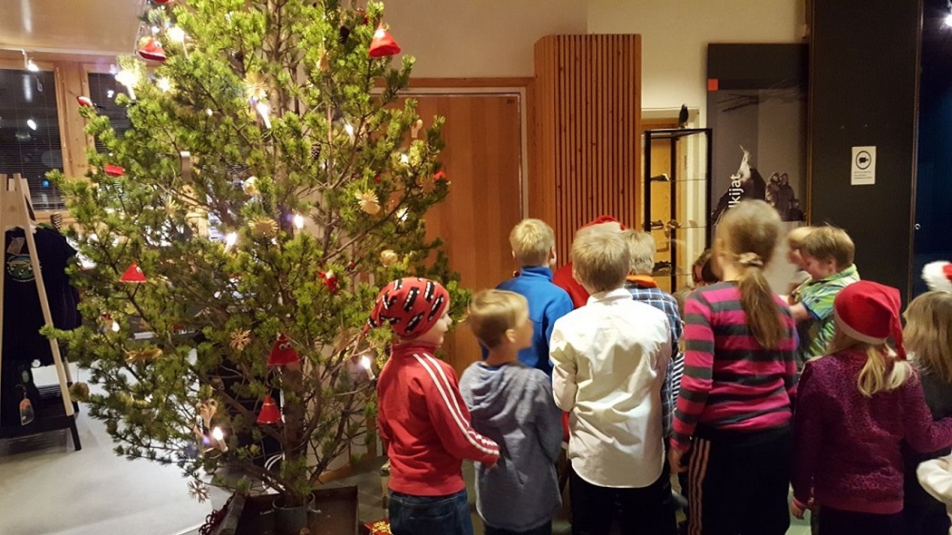 Joulukuusi koristeltuna ja vieressä seisomassa joukko lapsia.
